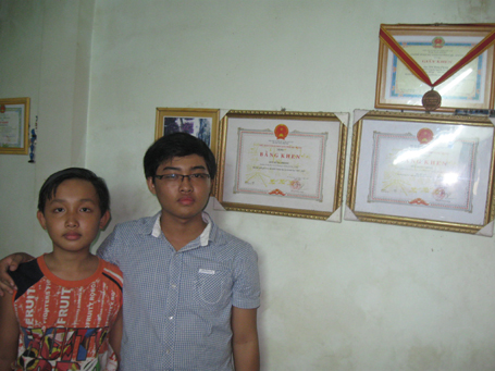 Em Sơn Hùng Phong cùng em trai bên bảng thành tích của mình.