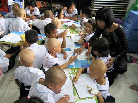 Cô giáo Đinh Thị Kim Phấn đang uốn nắn từng nét chữ cho bệnh nhi ung thư tại bệnh viện Ung bướu TP.HCM