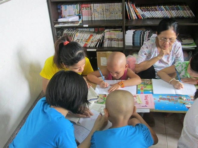 Bé Yến Vy, 6 tuổi, được các anh chị tình nguyện dạy tập viết sau khi mới được trở về từ phòng ICU (phòng chăm sóc đặc biệt)